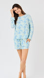 Woman wearing a light blue floral pajama set on a white background