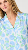 Woman wearing a floral patterned pajama set with blue and green flowers on a white background