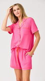 Woman wearing a pink pajama set with orange piping on a white background