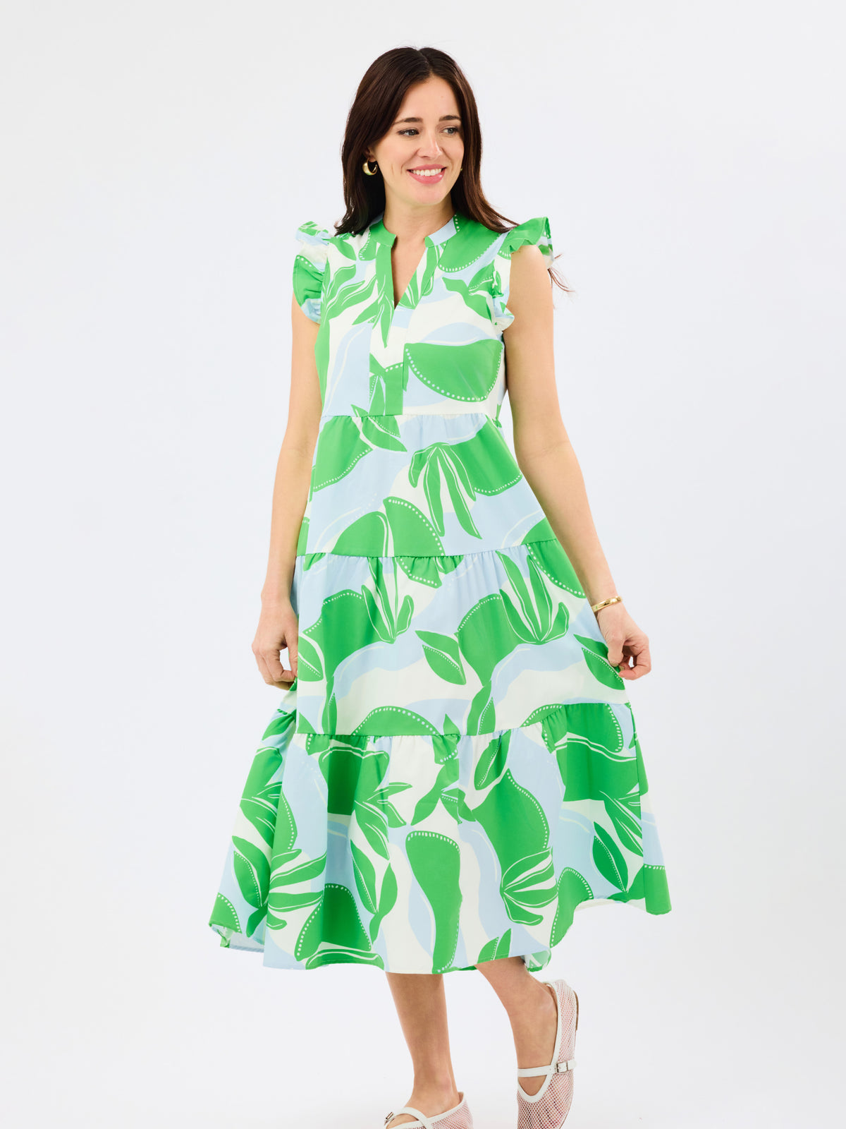 Woman wearing a green and white and blue leaf-patterned dress on a white background