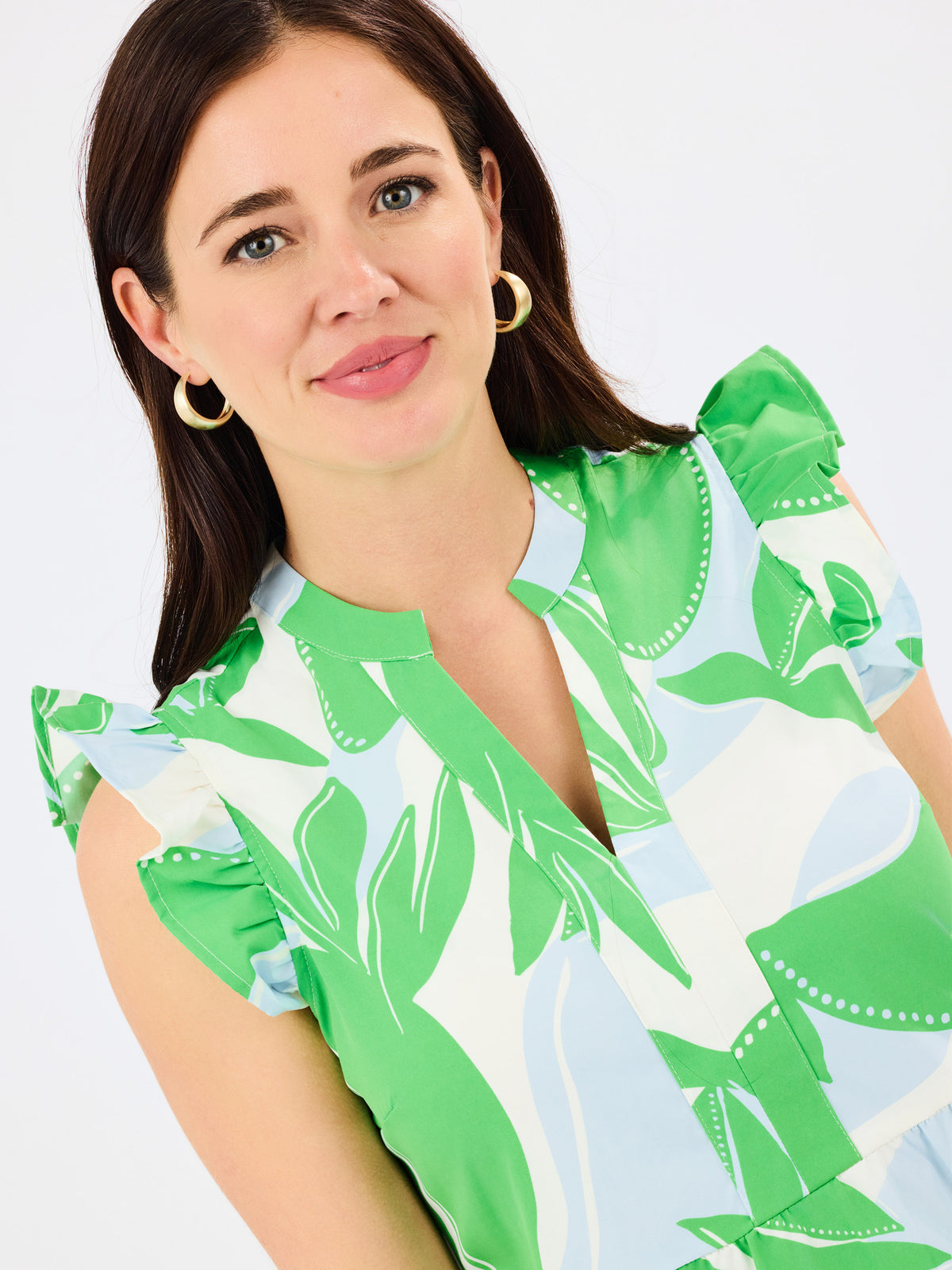 Woman wearing a green and white patterned dress on a plain background
