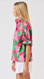 Woman wearing a green floral blouse with pink flowers on a white 
