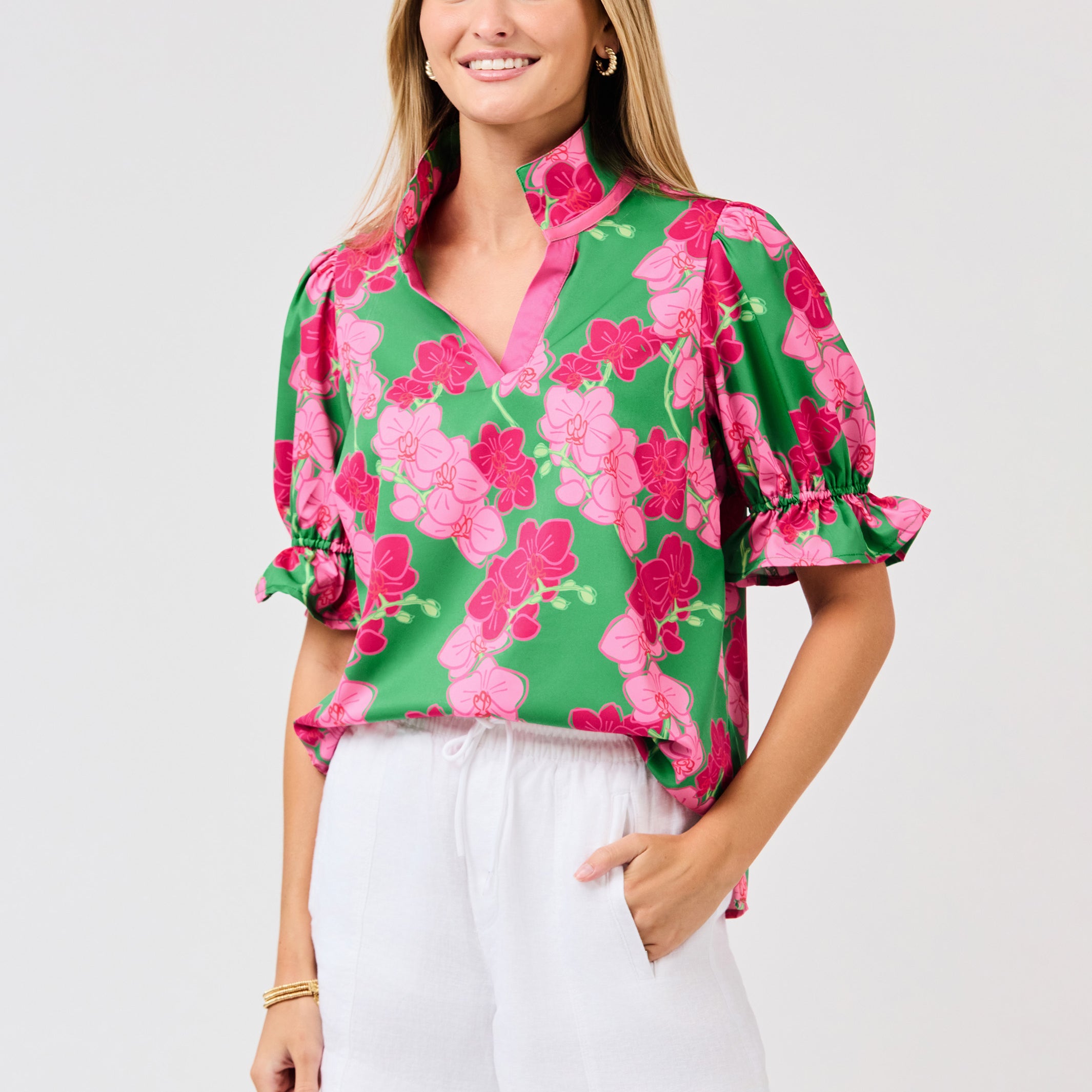 Woman wearing a green floral blouse with pink flowers on a white background