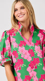 Woman wearing a green floral blouse with pink flowers on a white 