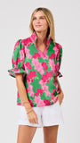 Woman wearing a green floral blouse with pink flowers on a white background
