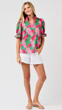 Woman wearing a green floral blouse with pink flowers on a white 