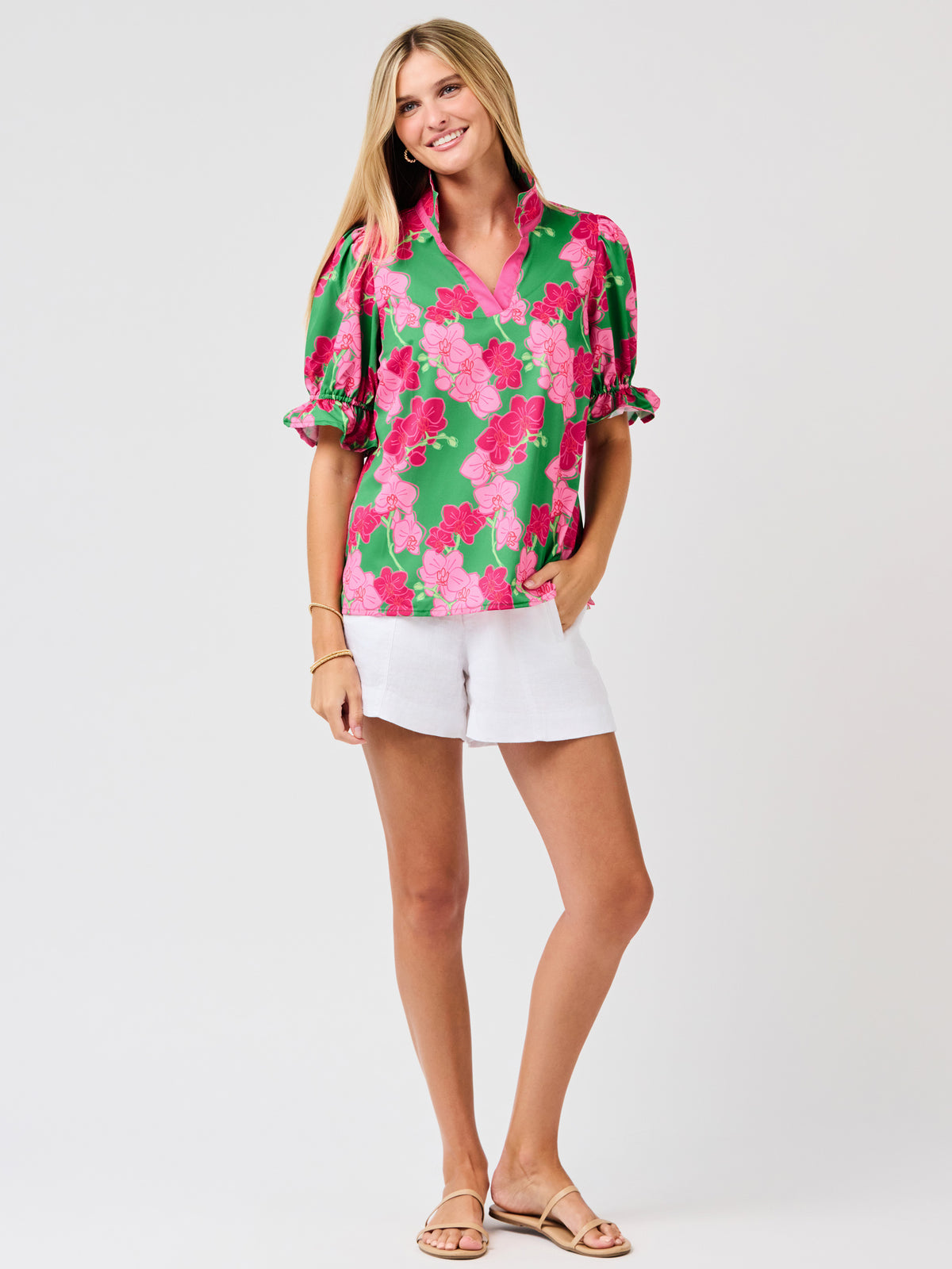Woman wearing a green floral blouse with pink flowers on a white 