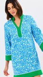 Woman wearing a blue floral dress with green trim on a white background