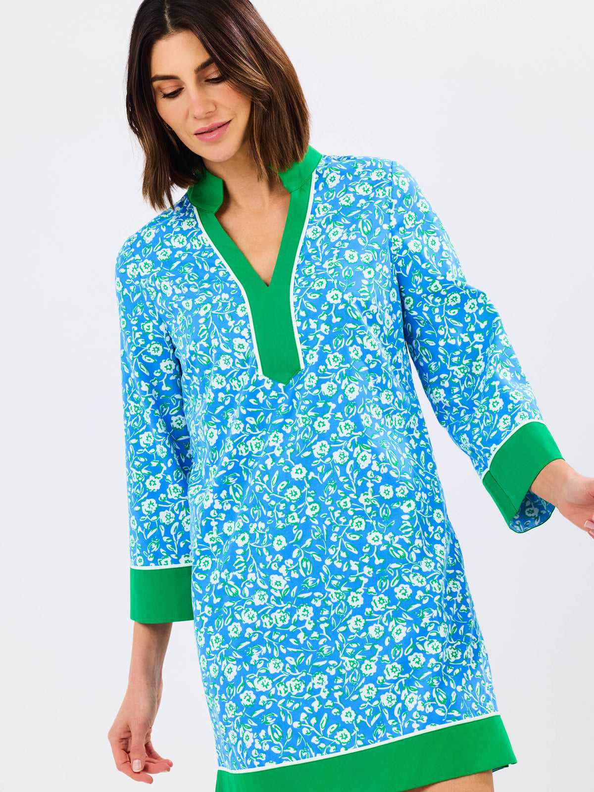 Woman wearing a blue floral dress with green trim on a white background