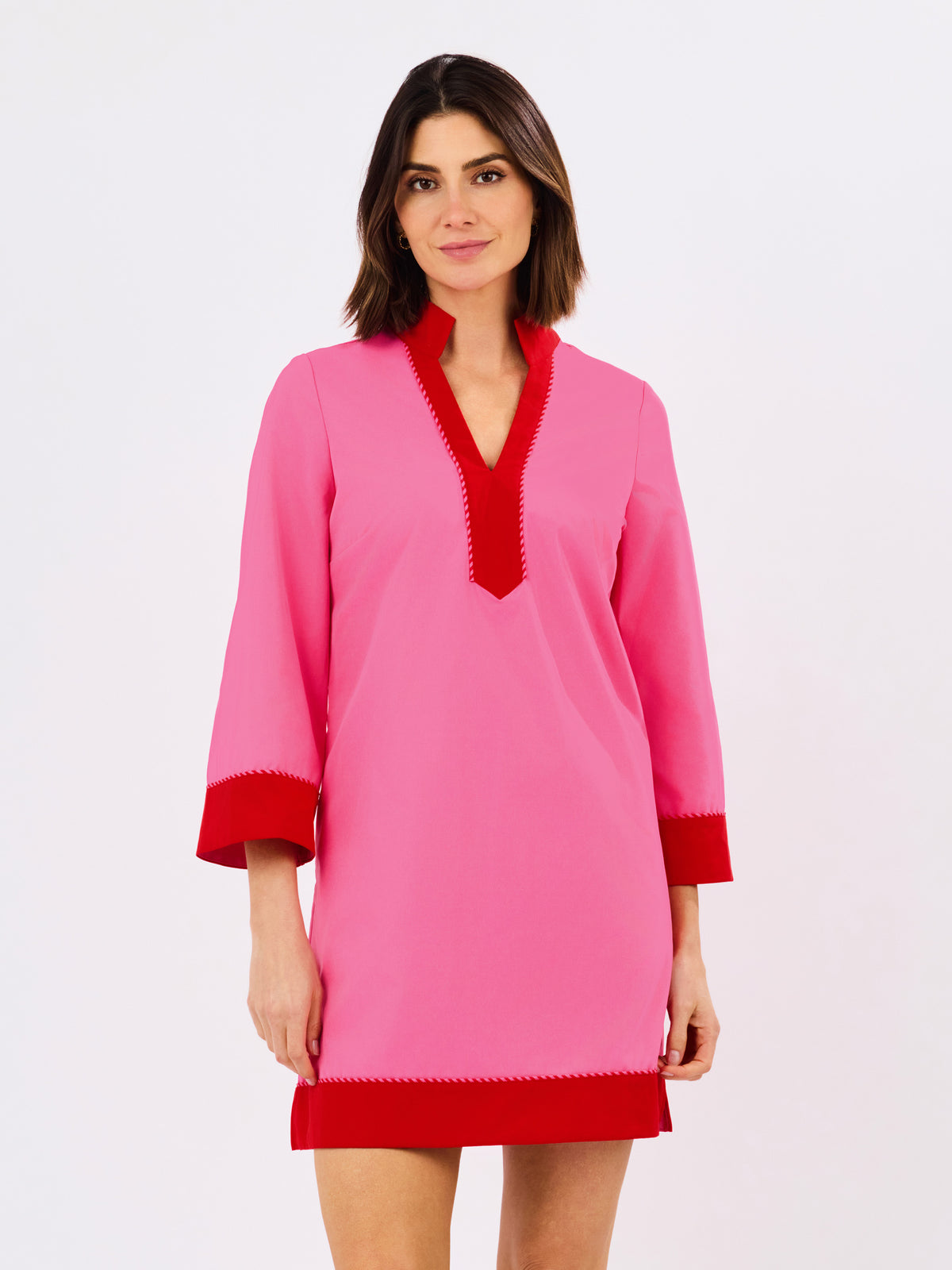 Woman wearing a pink dress with red accents on a white background