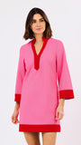 Woman wearing a pink dress with red trim on a white background