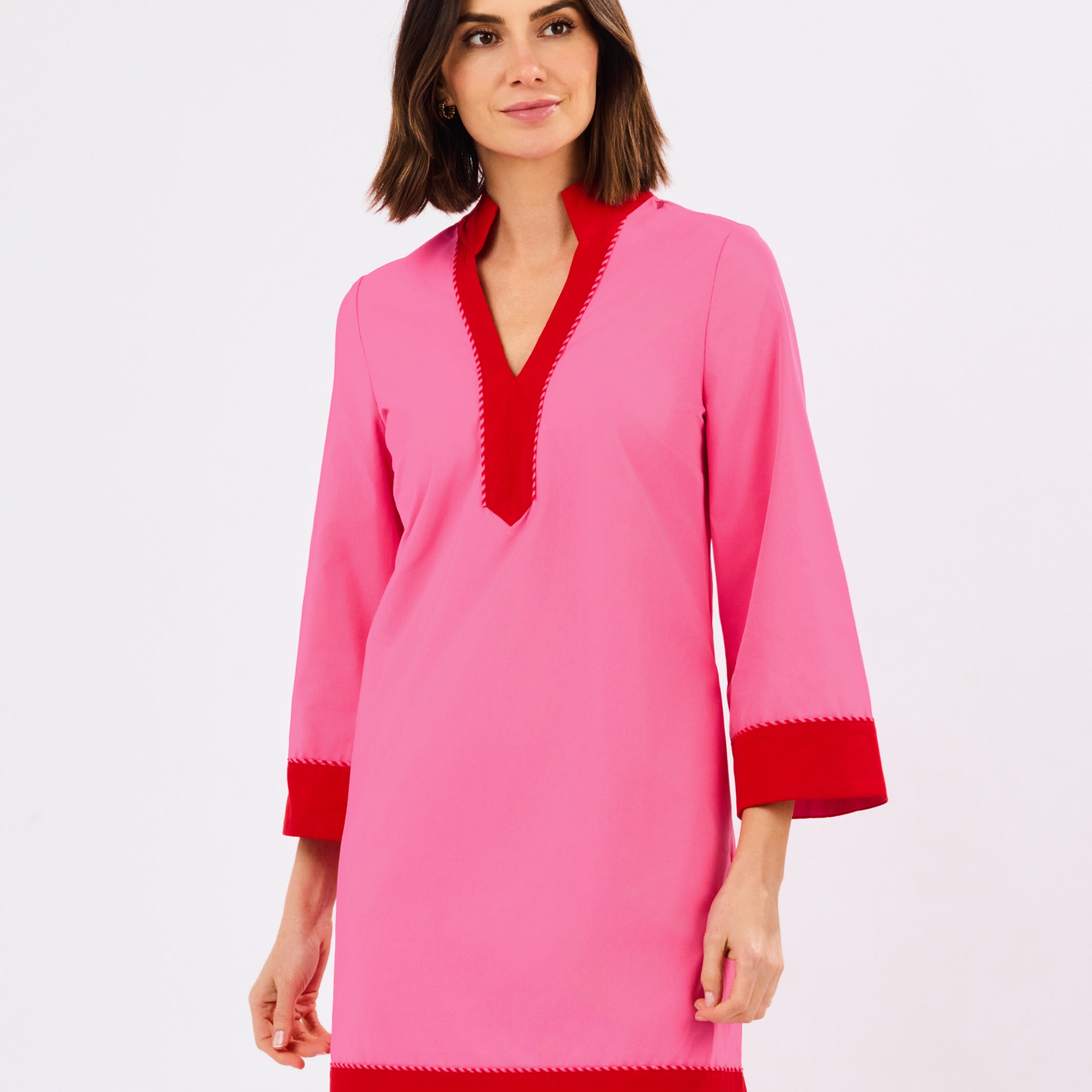 Woman wearing a pink dress with red trim on a white background