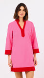 Woman wearing a pink dress with red trim on a white background