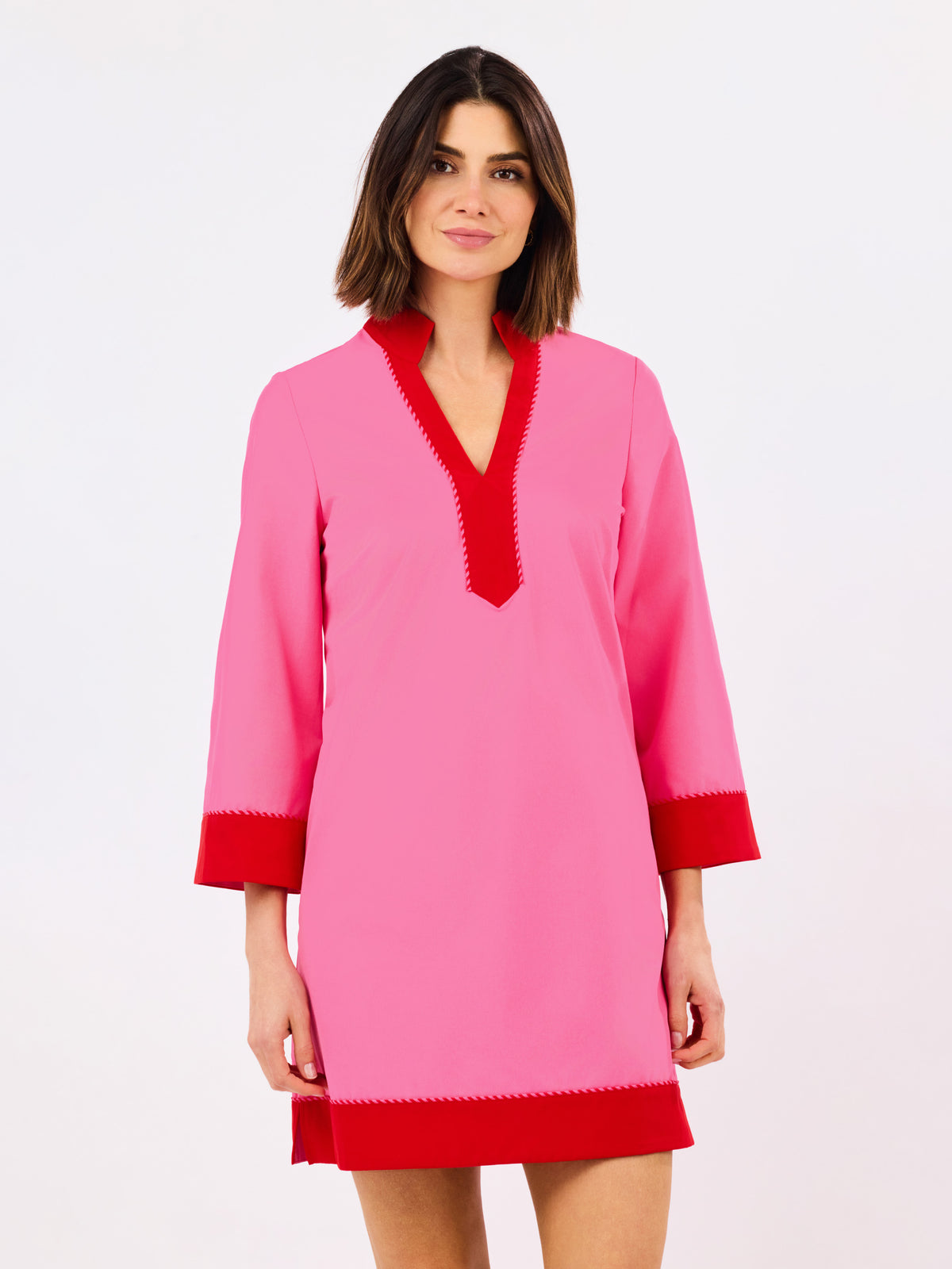 Woman wearing a pink dress with red trim on a white background
