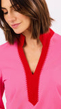 Woman wearing a pink top with a red neckline on a white background