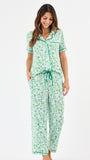 Woman wearing a green floral two piece pajama set with collar on a white background