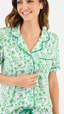 Woman wearing a green floral two piece pajama set with collar on a white background