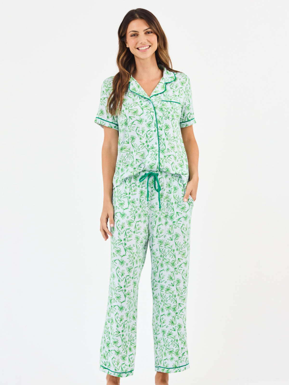 Woman wearing a green floral two piece pajama set with collar on a white background