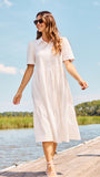 Woman in a white dress walking on a dock by a lake