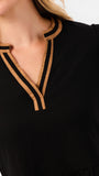 Close-up of a woman wearing a black long-sleeve top with a V-neckline trimmed in tan and black ribbed fabric.