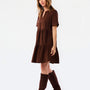 A woman modeling a short-sleeve brown tiered dress with a split neckline, paired with matching brown knee-high boots, against a plain white studio background.