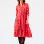 A woman modeling a red and orange floral print midi shirt dress with a matching tie belt, set against a plain white studio background.