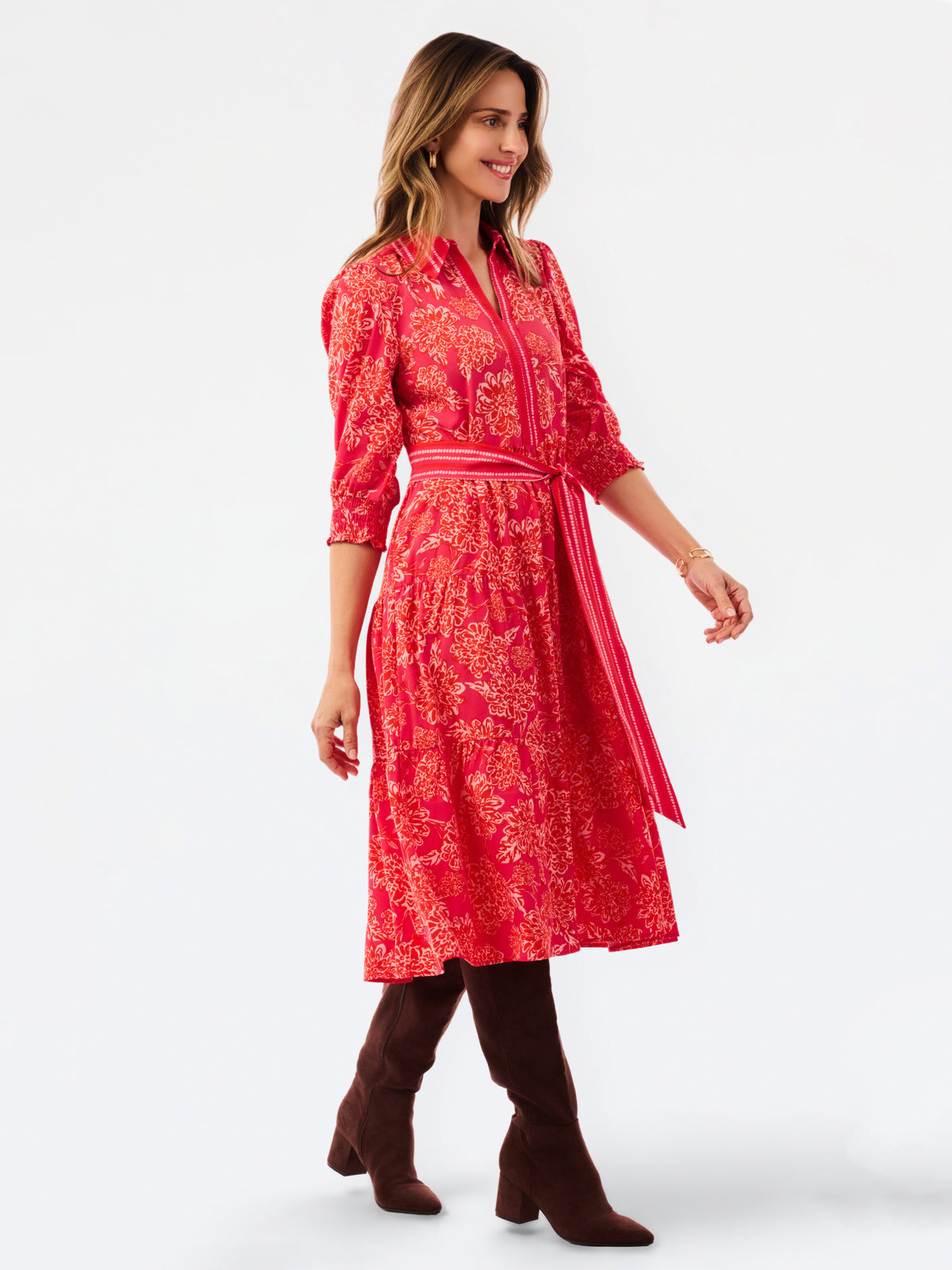 A woman modeling a red and orange floral print midi shirt dress with a matching tie belt, set against a plain white studio background.