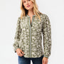 A woman modeling a long-sleeve button-up blouse with an olive green and cream floral pattern, paired with blue jeans, against a plain white studio background.