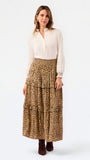 A woman modeling a white long-sleeve blouse and a tiered leopard-print maxi skirt, paired with dark brown ankle boots, against a plain white studio background.