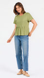 A woman wearing a sage green short-sleeve top with a gathered peplum hem, paired with blue jeans, against a plain white background.