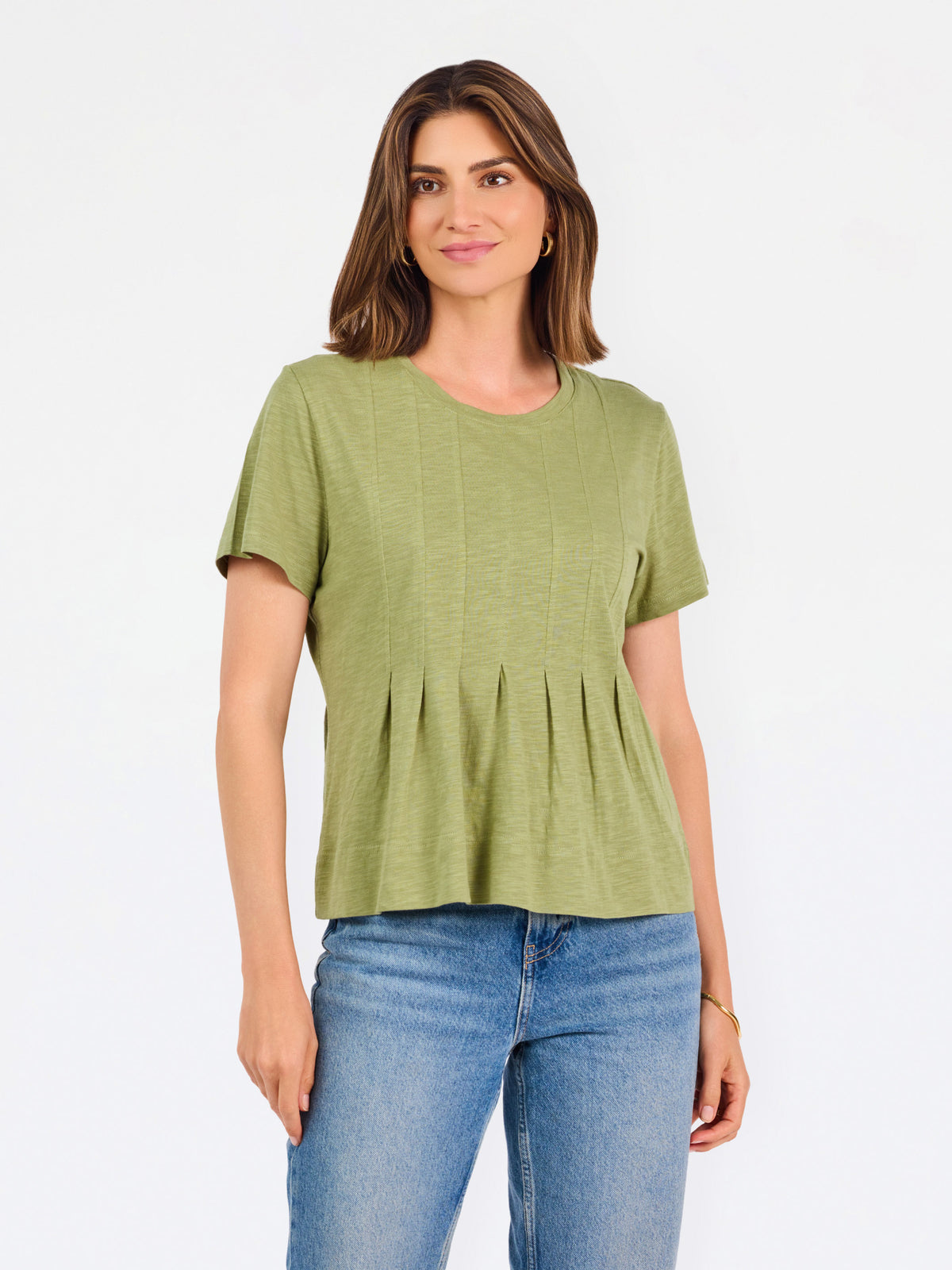 A woman wearing a sage green short-sleeve top with a gathered peplum hem, paired with blue jeans, against a plain white background.