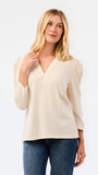 A blonde woman modeling a white long-sleeve knit top with a V-neck and puffed shoulders, paired with blue jeans, against a plain white studio background.
