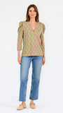 A woman modeling a green long-sleeve blouse with a pink floral pattern, puff sleeves, and a split V-neckline, paired with blue jeans against a plain white background.