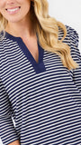 A close-up of a woman wearing a navy blue and white horizontally striped long-sleeve top with a V-neckline.