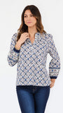 A woman modeling a long-sleeve button-up blouse with a blue and white geometric block print pattern, paired with dark blue jeans, against a plain white studio background.