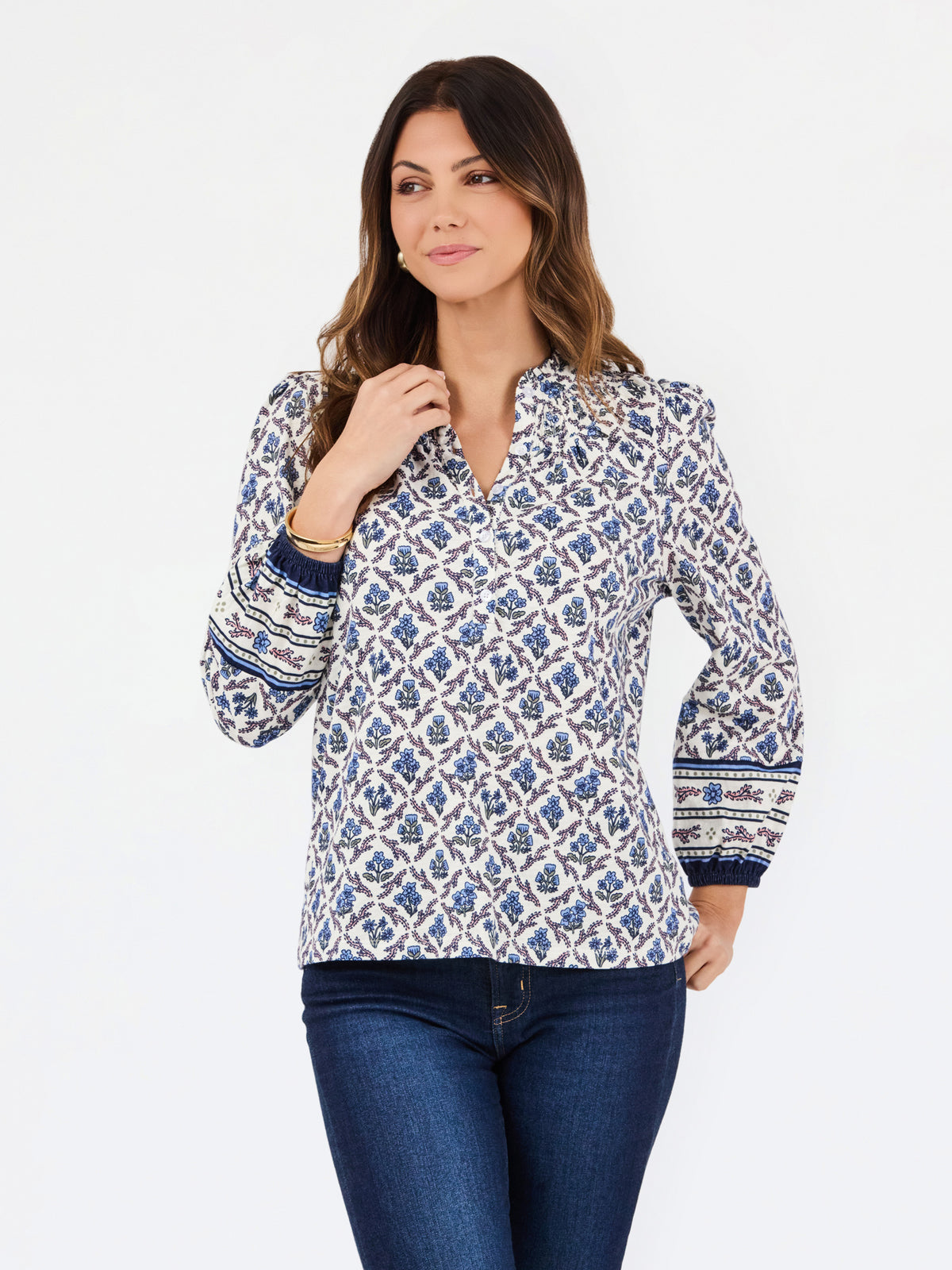 A woman modeling a long-sleeve button-up blouse with a blue and white geometric block print pattern, paired with dark blue jeans, against a plain white studio background.