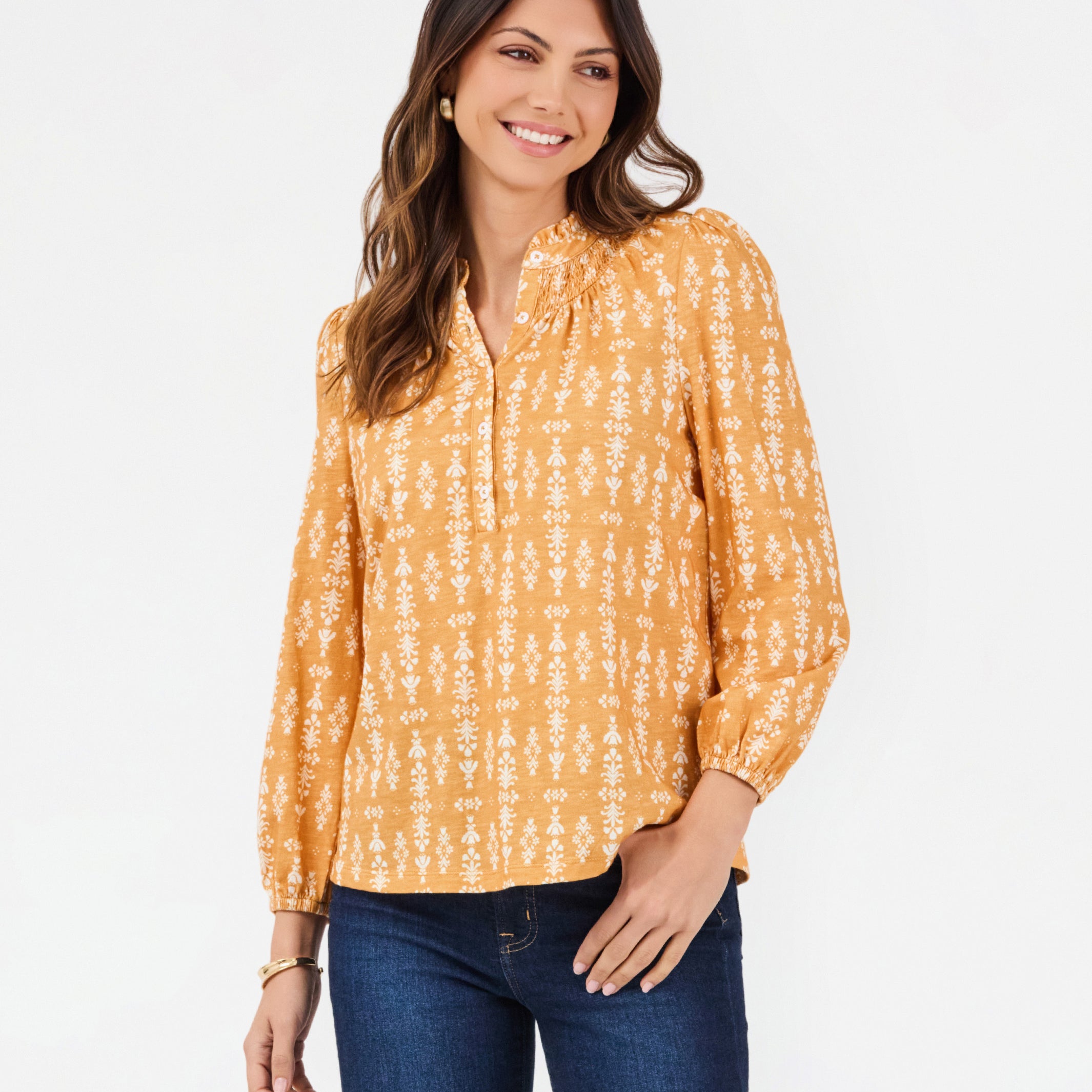 A woman modeling a long-sleeve yellow blouse with a white vertical pattern, paired with dark blue jeans, against a plain white background.