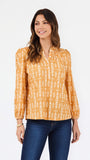 A woman modeling a long-sleeve blouse with a mustard yellow and white vertical pattern, paired with dark blue jeans, against a plain white studio background.