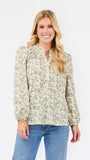 A woman modeling a long-sleeve blouse with a green and beige floral pattern, paired with blue jeans, against a plain white studio background.