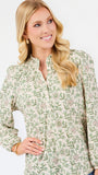 A woman modeling a long-sleeve blouse with a green and beige floral pattern, paired with blue jeans, against a plain white studio background.