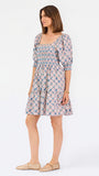 Women with short brown hair wearing a mini dress with puff sleeve lattice printed dress with pink and blue floral wearing gold flats
