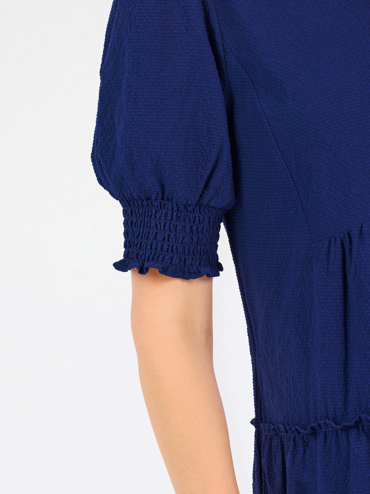 Women with short brown hair wearing a navy blue mini dress with puff sleeves and seersucker 