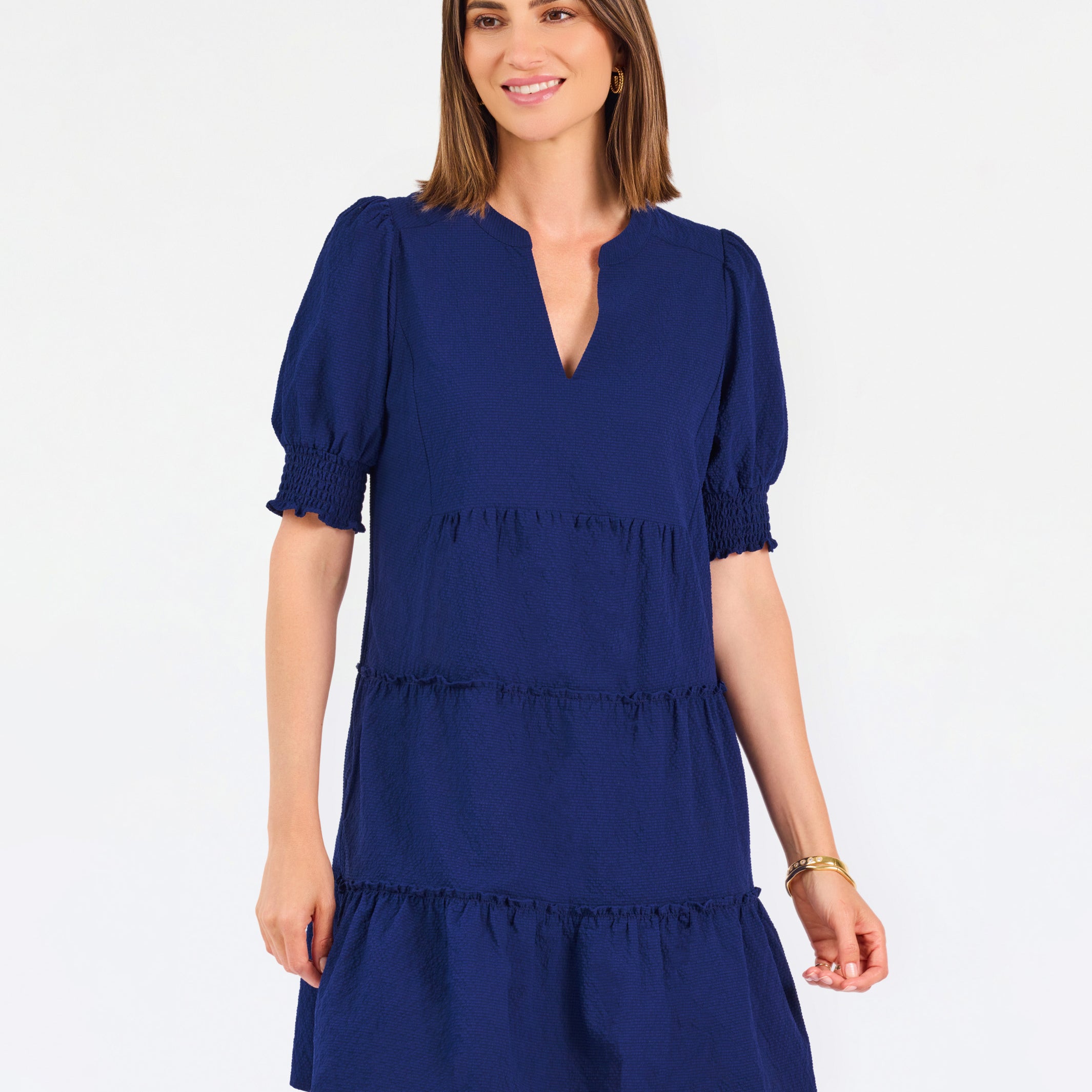 Women with short brown hair wearing a navy blue mini dress with puff sleeves and seersucker 