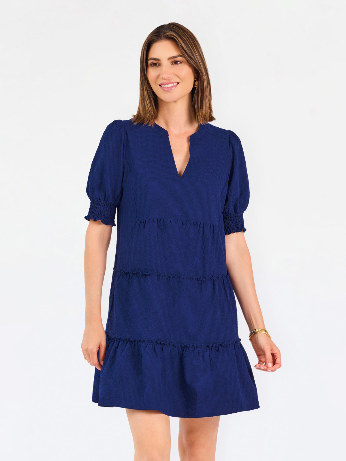 Women with short brown hair wearing a navy blue mini dress with puff sleeves and seersucker 