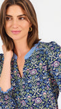 Women with short brown hair wearing a blue printed mini dress with three quarter puff sleeves and blue trim 