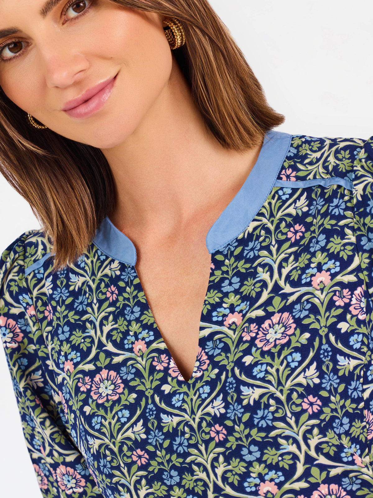 Women with short brown hair wearing a blue printed mini dress with three quarter puff sleeves and blue trim 