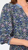 Women with short brown hair wearing a blue printed mini dress with three quarter puff sleeves and blue trim 