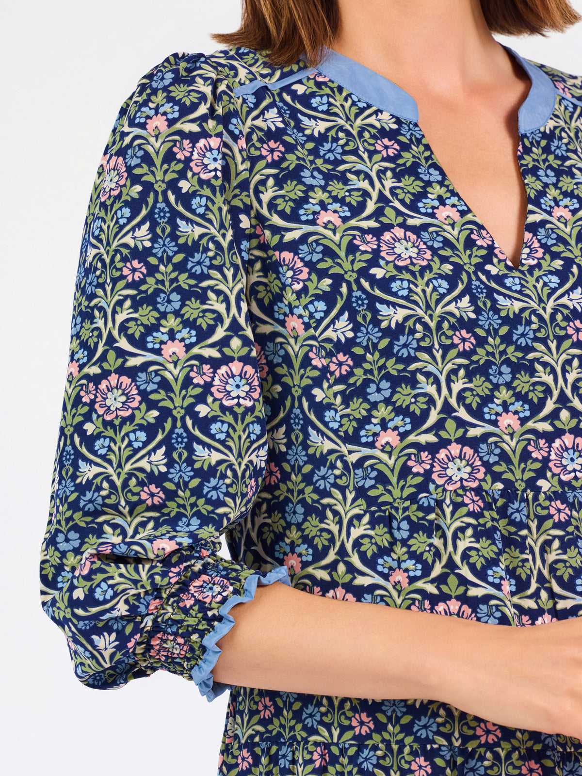 Women with short brown hair wearing a blue printed mini dress with three quarter puff sleeves and blue trim 