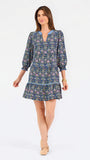 Women with short brown hair wearing a blue printed mini dress with three quarter puff sleeves and blue trim 