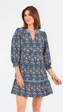 Women with short brown hair wearing a blue printed mini dress with three quarter puff sleeves and blue trim 